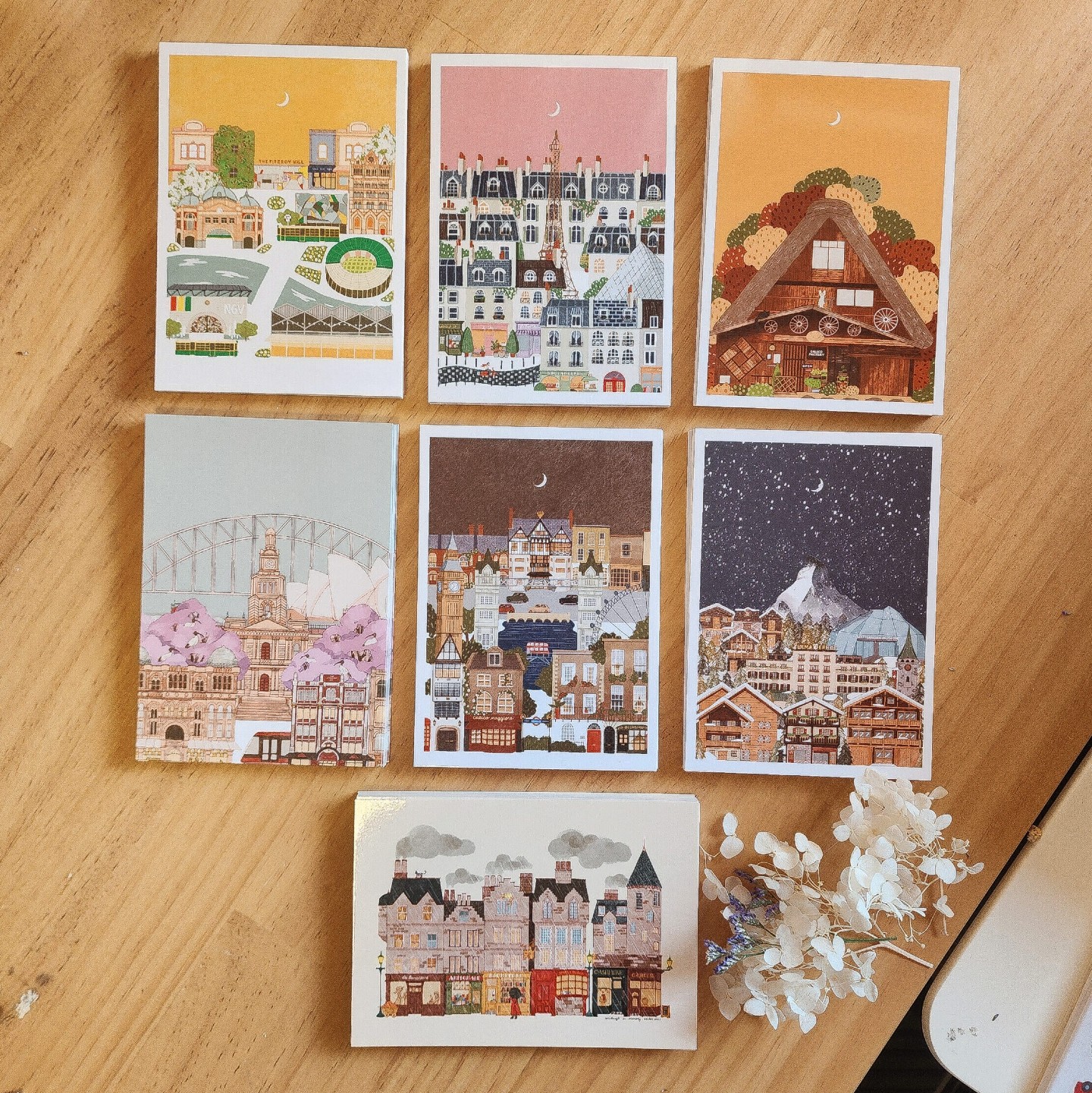 Illustrated travel postcard set arranged on a wooden desk